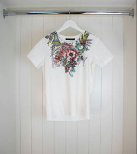 Florales Basic Shirt aus 95% Baumwolle und 5% Elasthan mit Placement und Glitzersteinen. Die taillierte Passform ergänzt das Design perfekt.